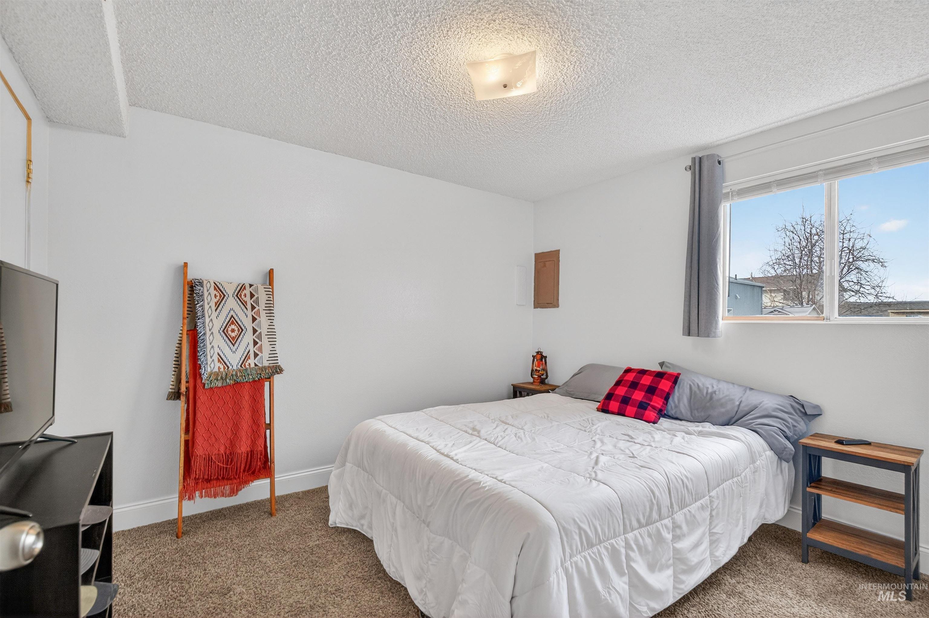 Carpeted bedroom with a textured ceiling and baseboards