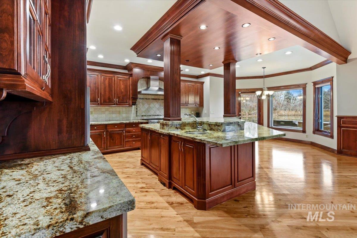 Kitchen featuring pendant lighting, light stone countertops, an island with sink, light wood-style flooring, and recessed lighting