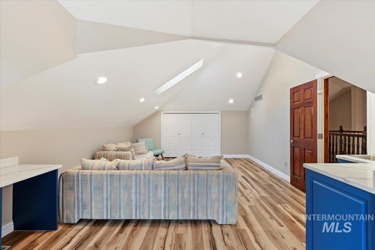 Bonus room with a skylight, light wood finished floors, lofted ceiling, and recessed lighting