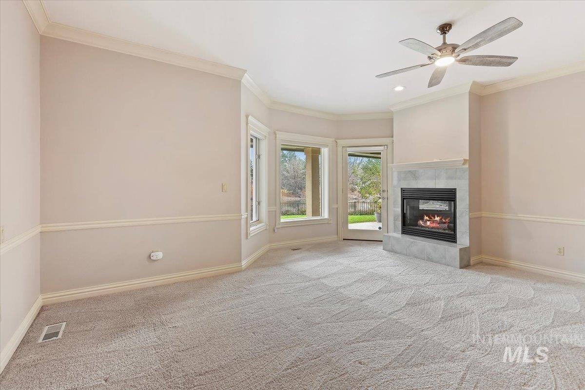 Unfurnished living room featuring crown molding, a tiled fireplace, light colored carpet, ceiling fan, and recessed lighting