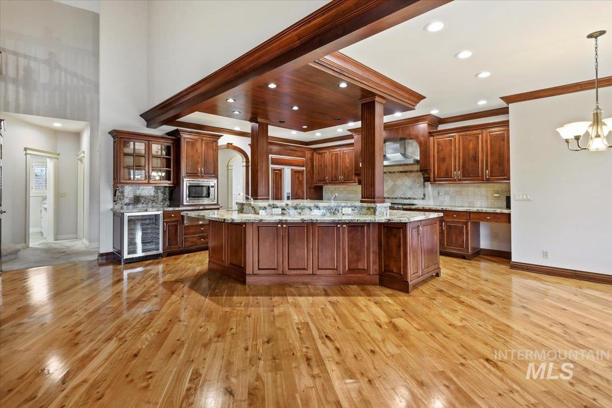 Kitchen featuring glass insert cabinets, tasteful backsplash, wine cooler, a chandelier, and recessed lighting