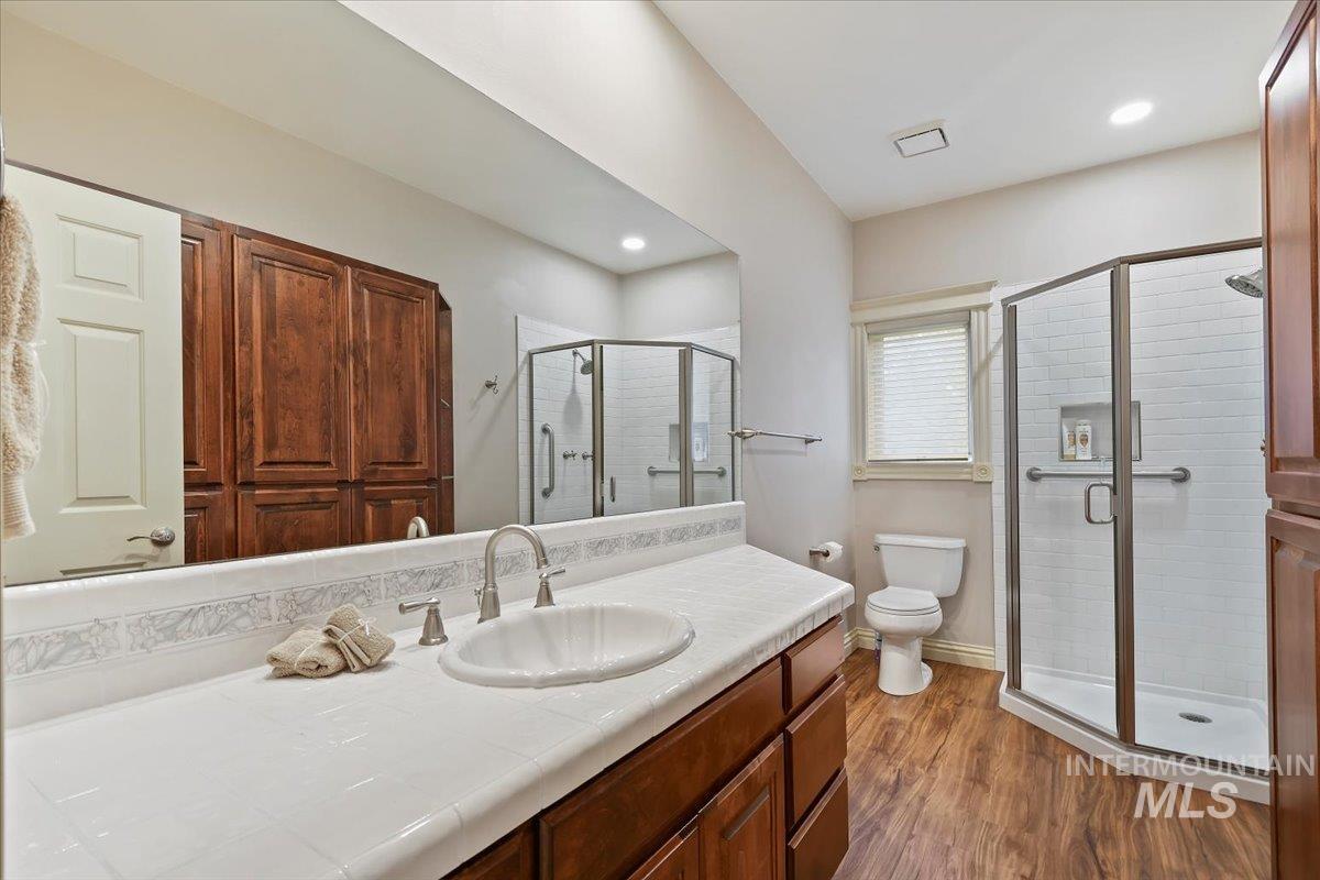 Bathroom with vanity, a shower stall, and dark wood-style floors
