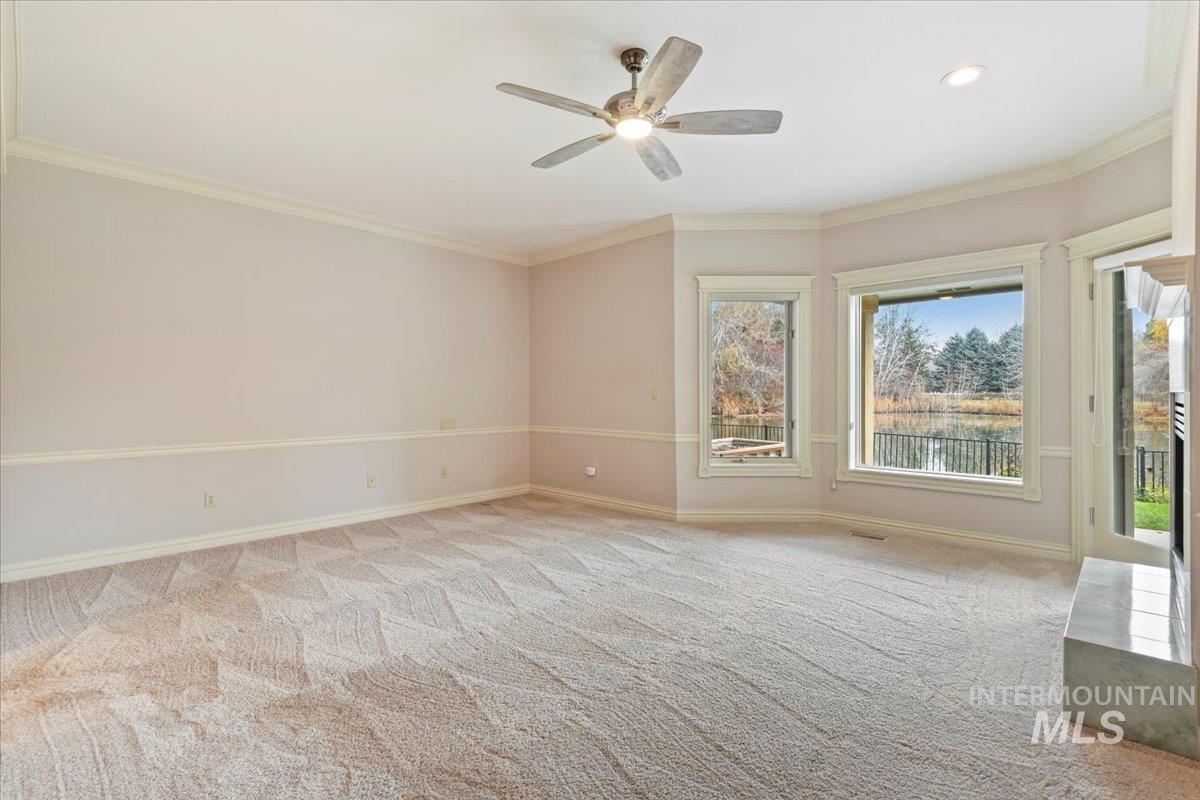 Spare room featuring crown molding, light carpet, and a ceiling fan