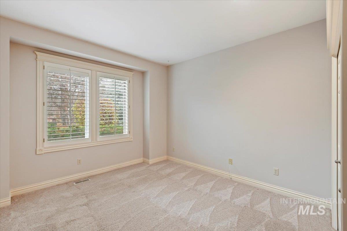 Unfurnished room featuring light carpet and baseboards
