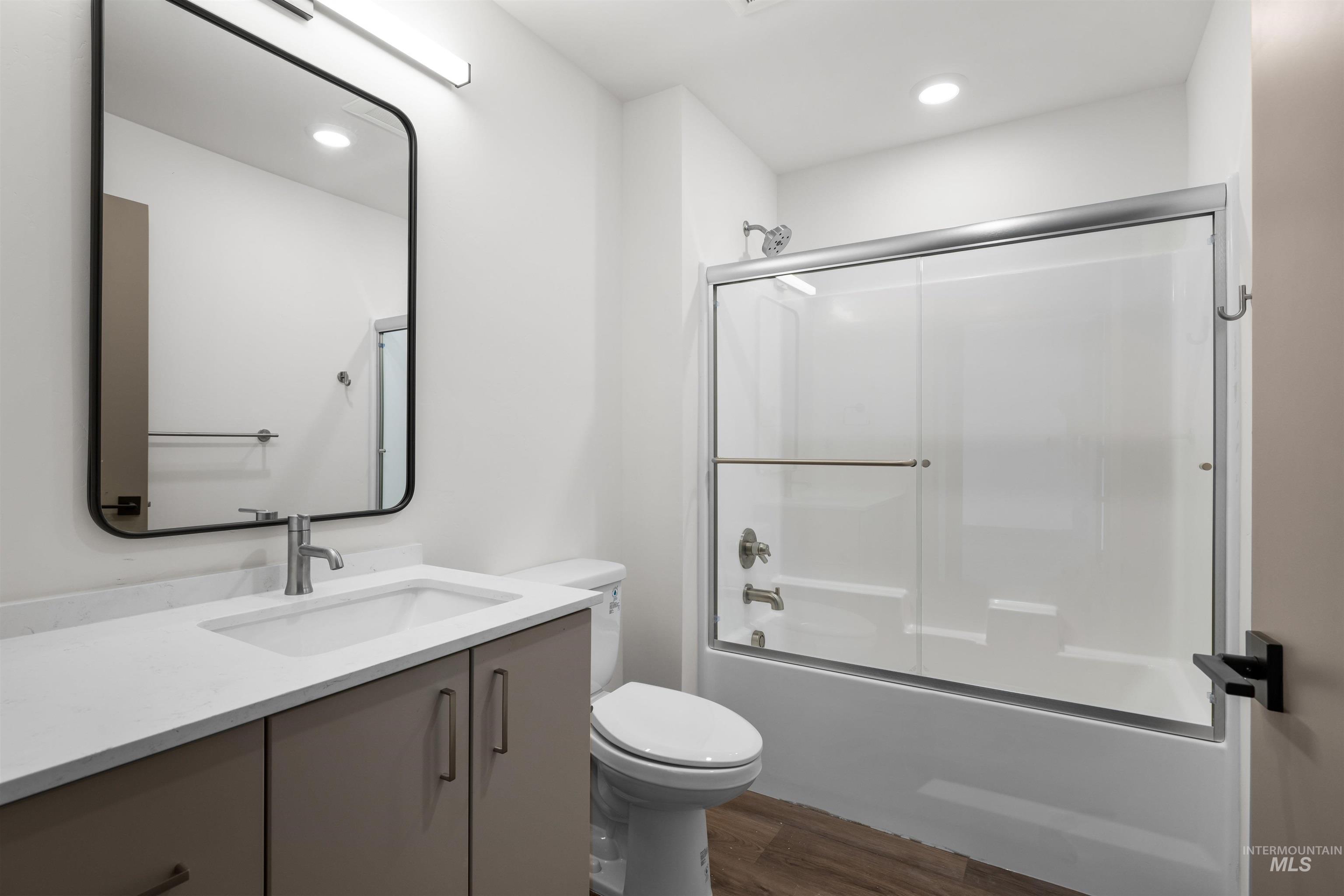 Full bath featuring vanity, bath / shower combo with glass door, recessed lighting, and dark wood finished floors