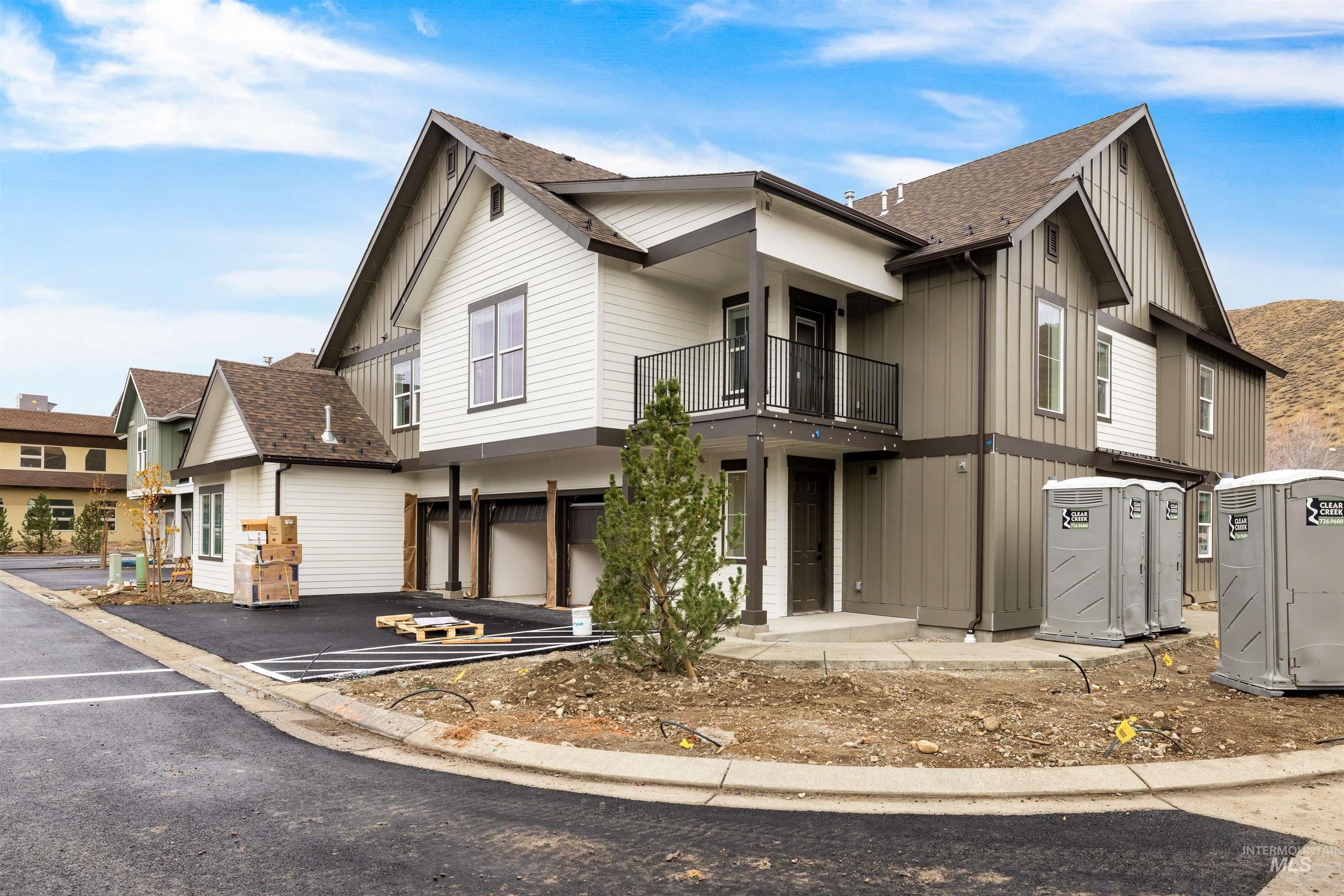 View of front of house featuring a balcony, roof with shingles, board and batten siding, a garage, and driveway