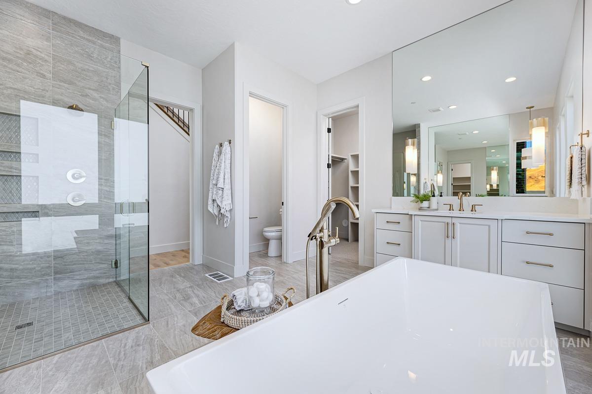 Full bathroom featuring a walk in closet, a shower stall, vanity, a soaking tub, and recessed lighting