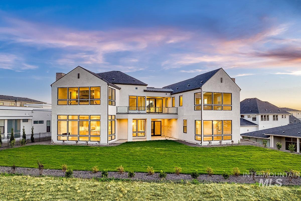 Back of house at dusk featuring a balcony, stucco siding, and a patio area