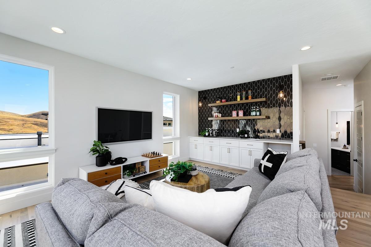 Living room featuring light wood-style flooring, bar area, and recessed lighting