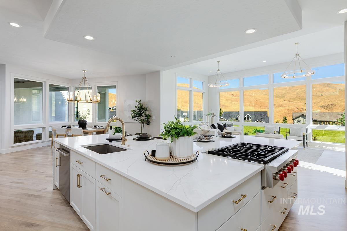 Kitchen with a chandelier, white cabinetry, light stone countertops, an island with sink, and stainless steel appliances