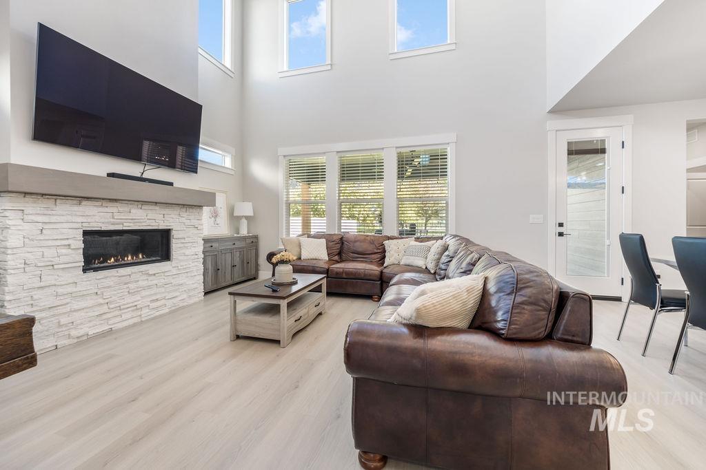 Living room featuring a high ceiling, light wood-style floors, and a fireplace