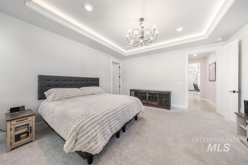 Bedroom with a tray ceiling, carpet flooring, a chandelier, and recessed lighting
