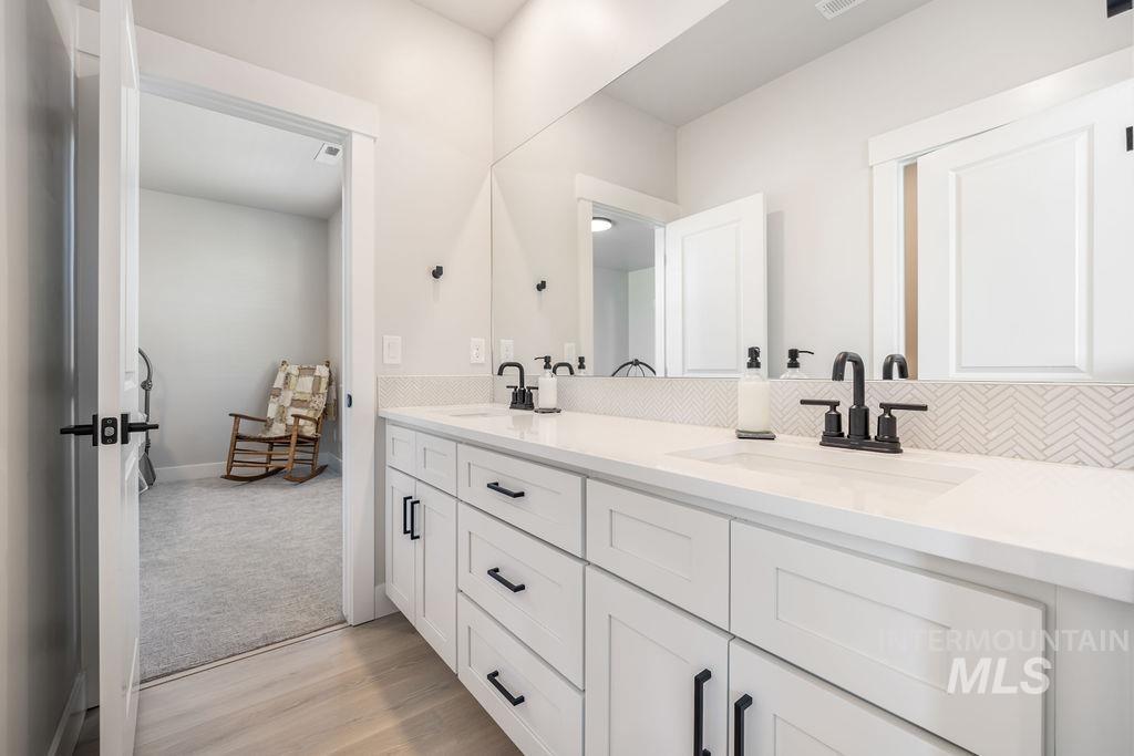 Bathroom featuring double vanity and light wood-type flooring