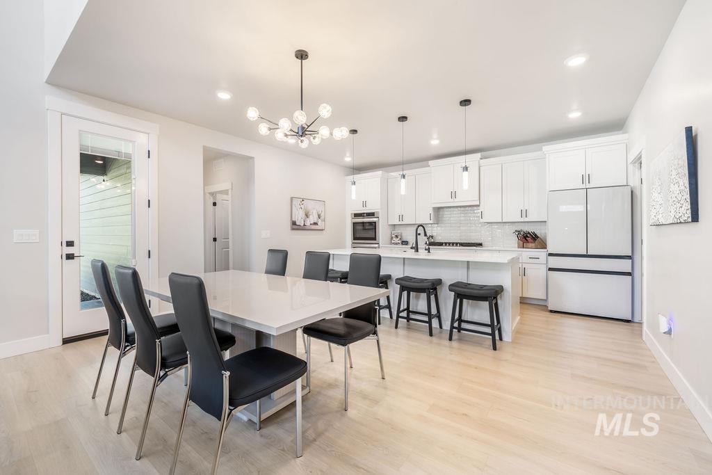 Dining space with a chandelier, light wood-style flooring, and recessed lighting