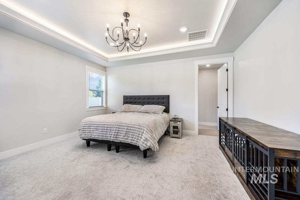 Bedroom featuring carpet flooring, a chandelier, a tray ceiling, and recessed lighting