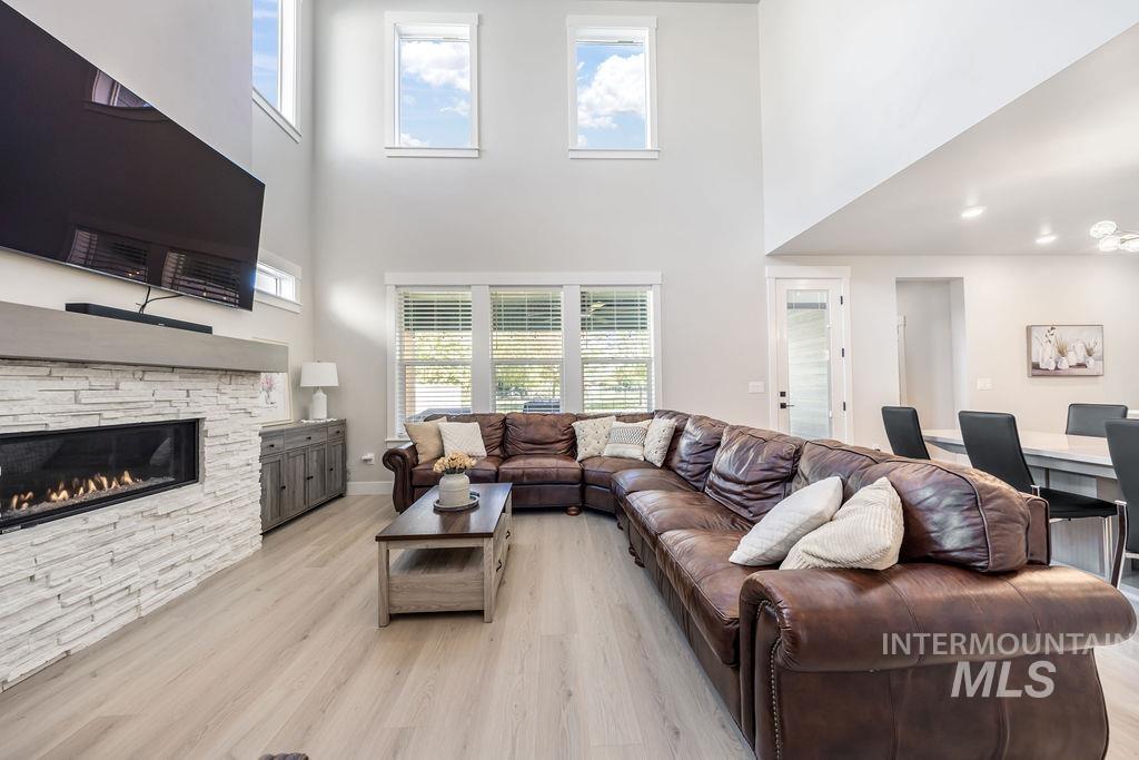 Living room with a high ceiling, light wood-style flooring, healthy amount of natural light, and a fireplace