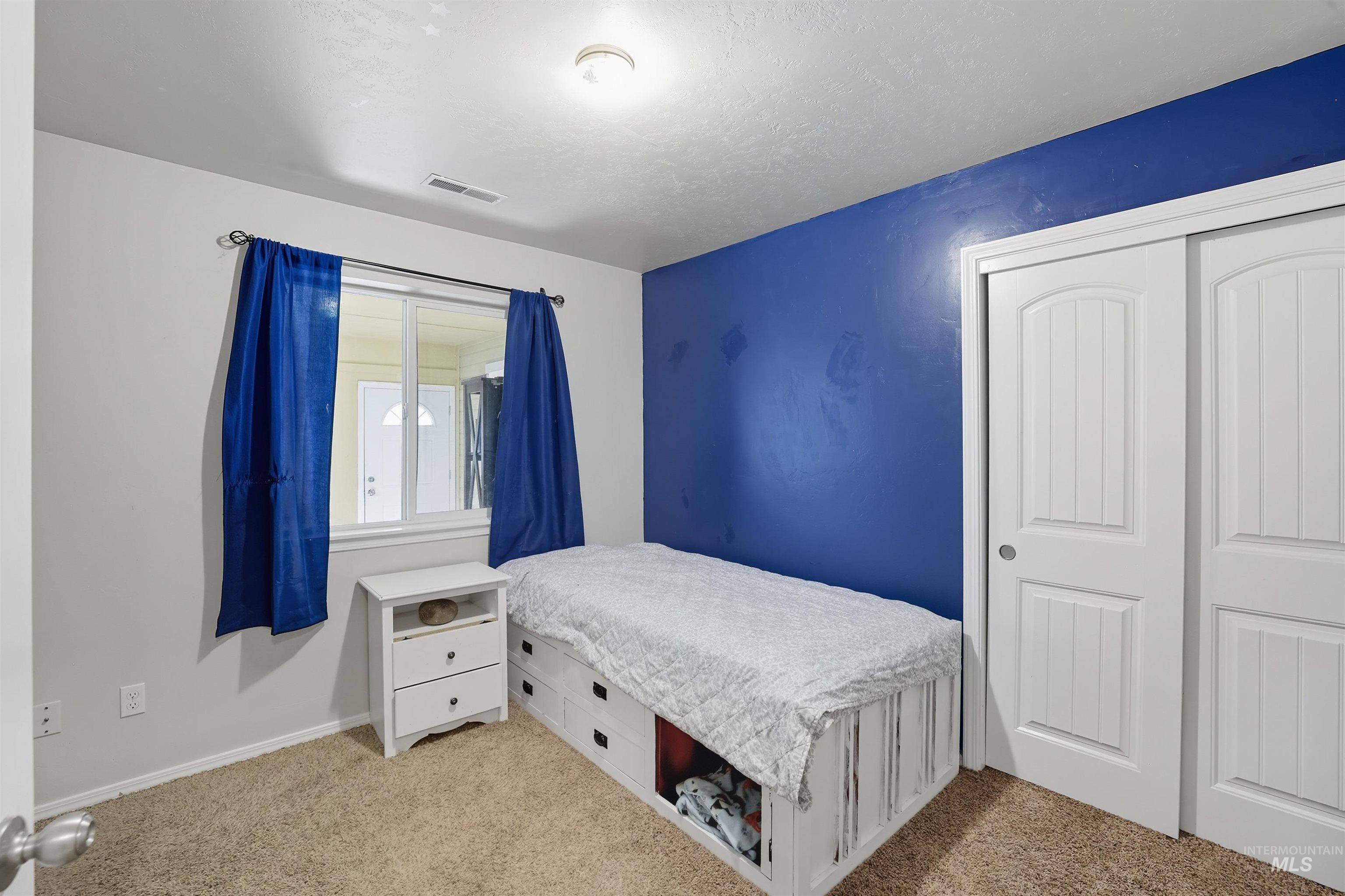 Bedroom with light colored carpet, a closet, and a textured ceiling