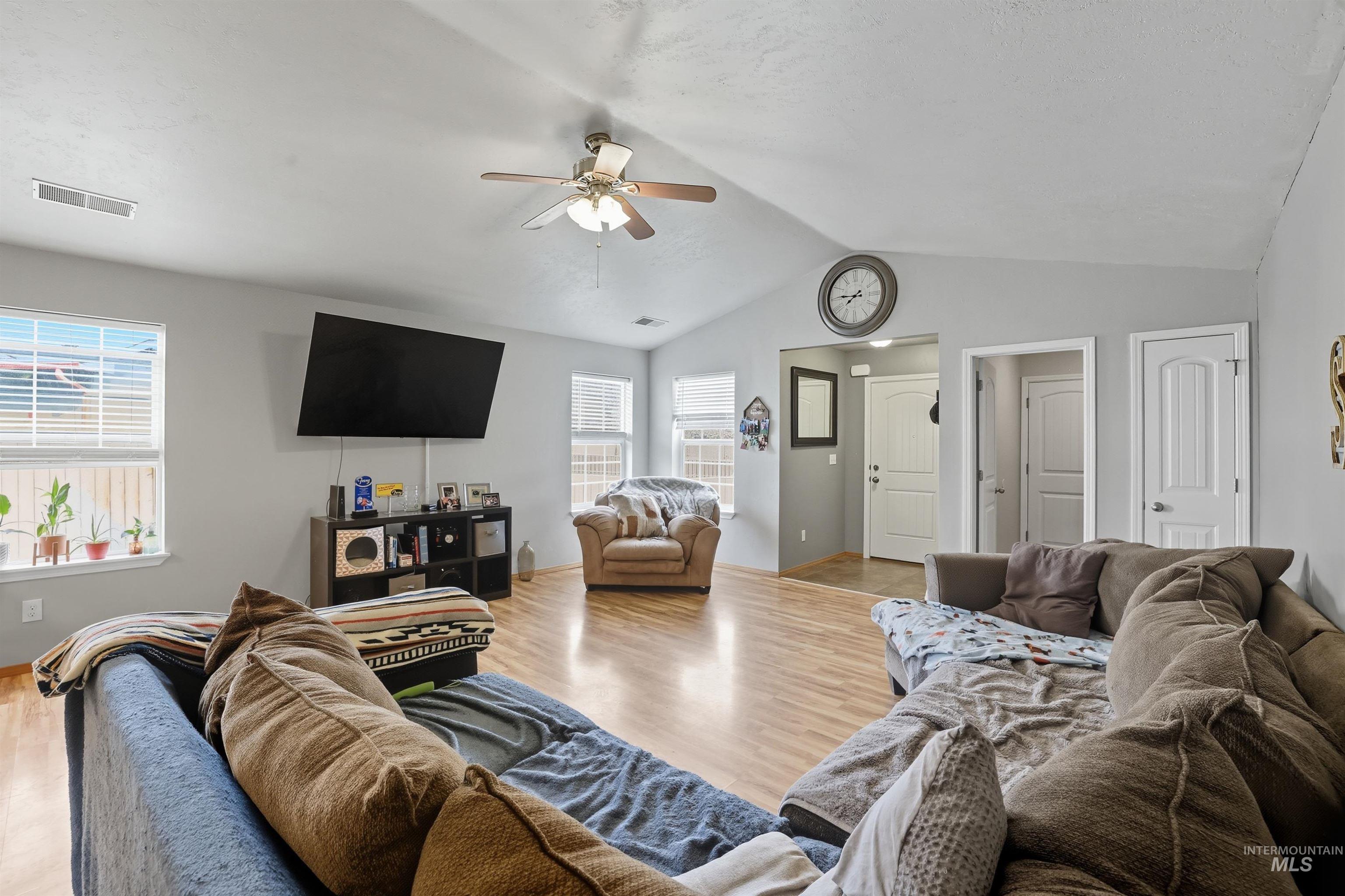 Living area with light wood finished floors, vaulted ceiling, and ceiling fan