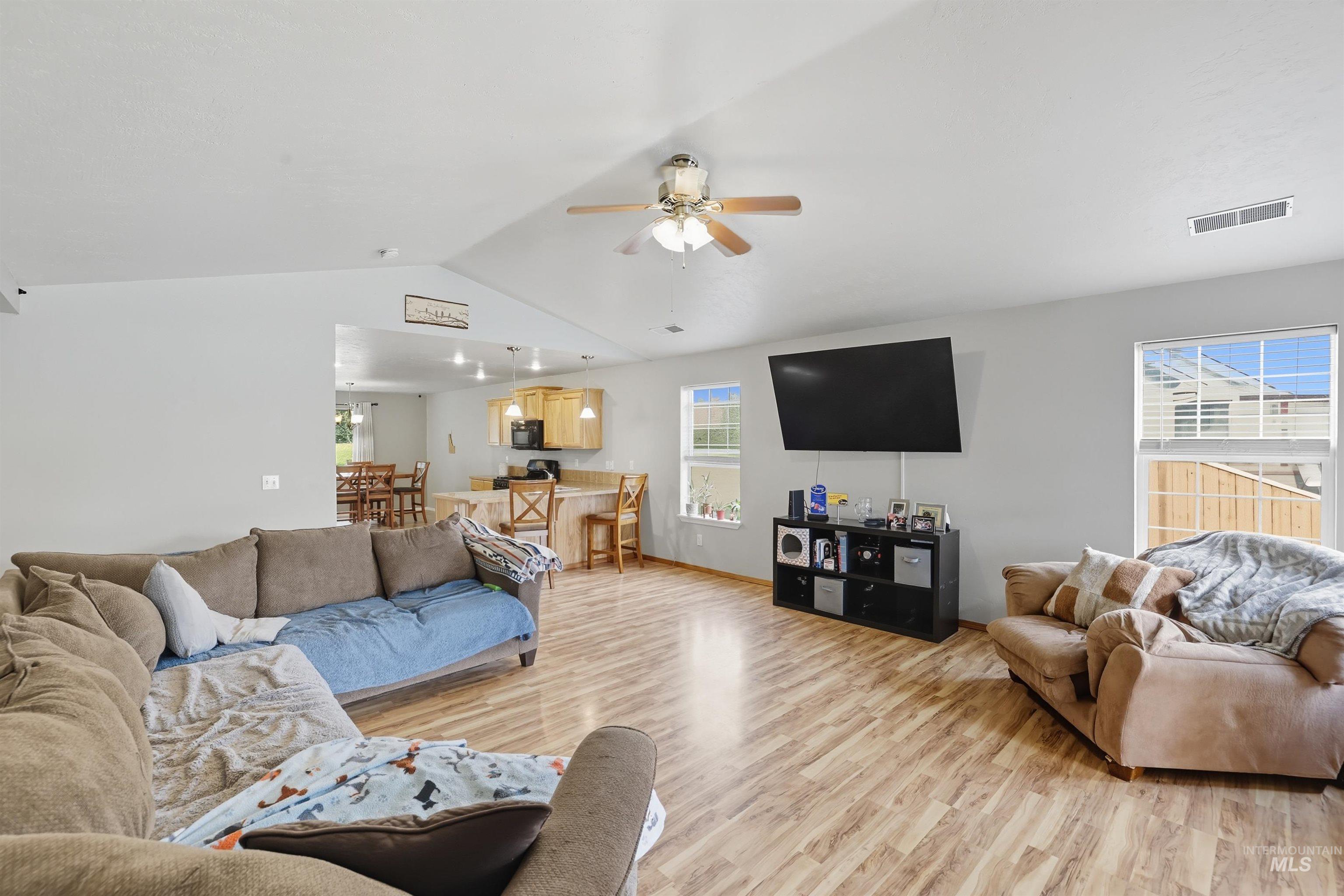 Living room with light wood-type flooring, lofted ceiling, plenty of natural light, and a ceiling fan