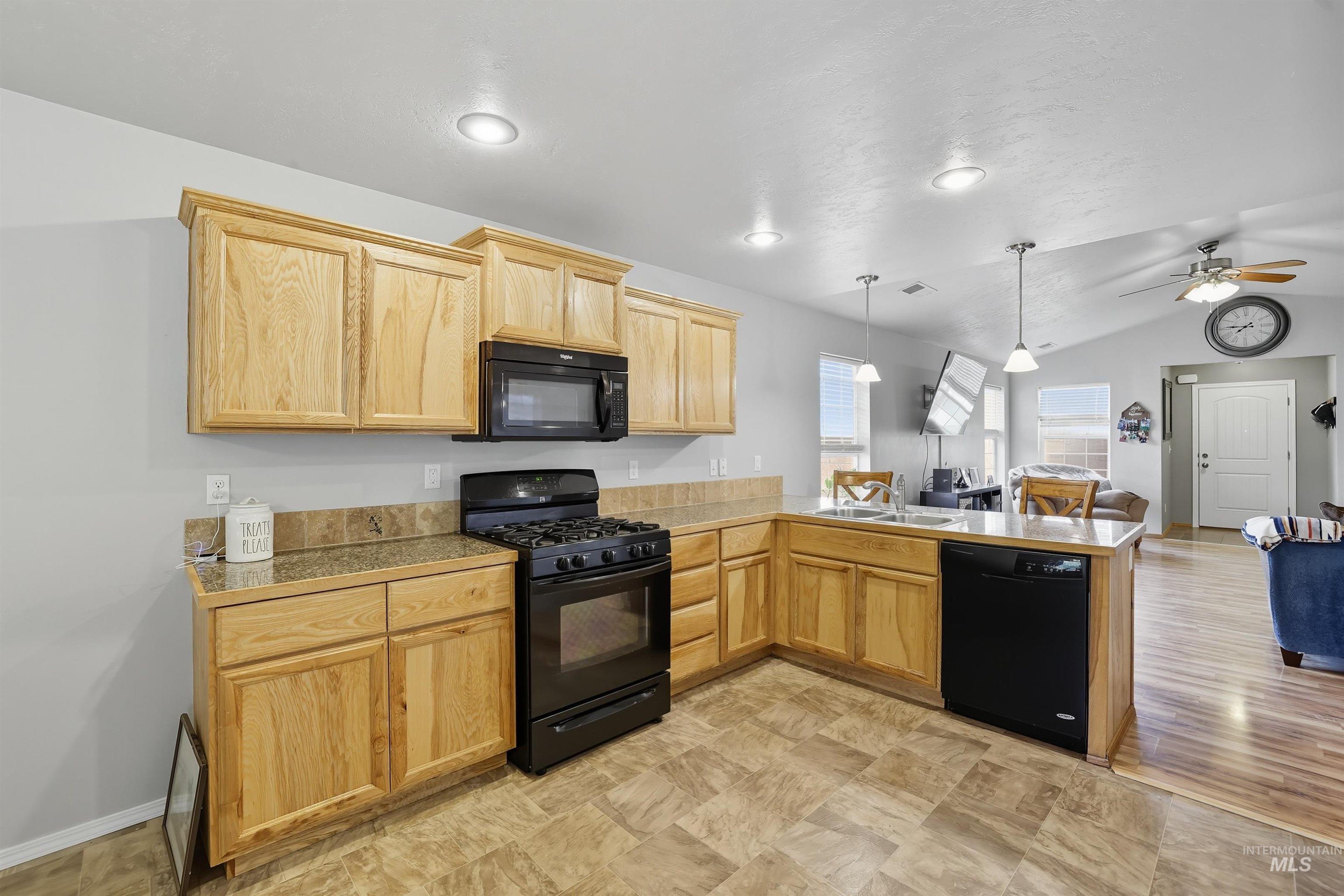 Kitchen with black appliances, open floor plan, pendant lighting, a peninsula, and a ceiling fan