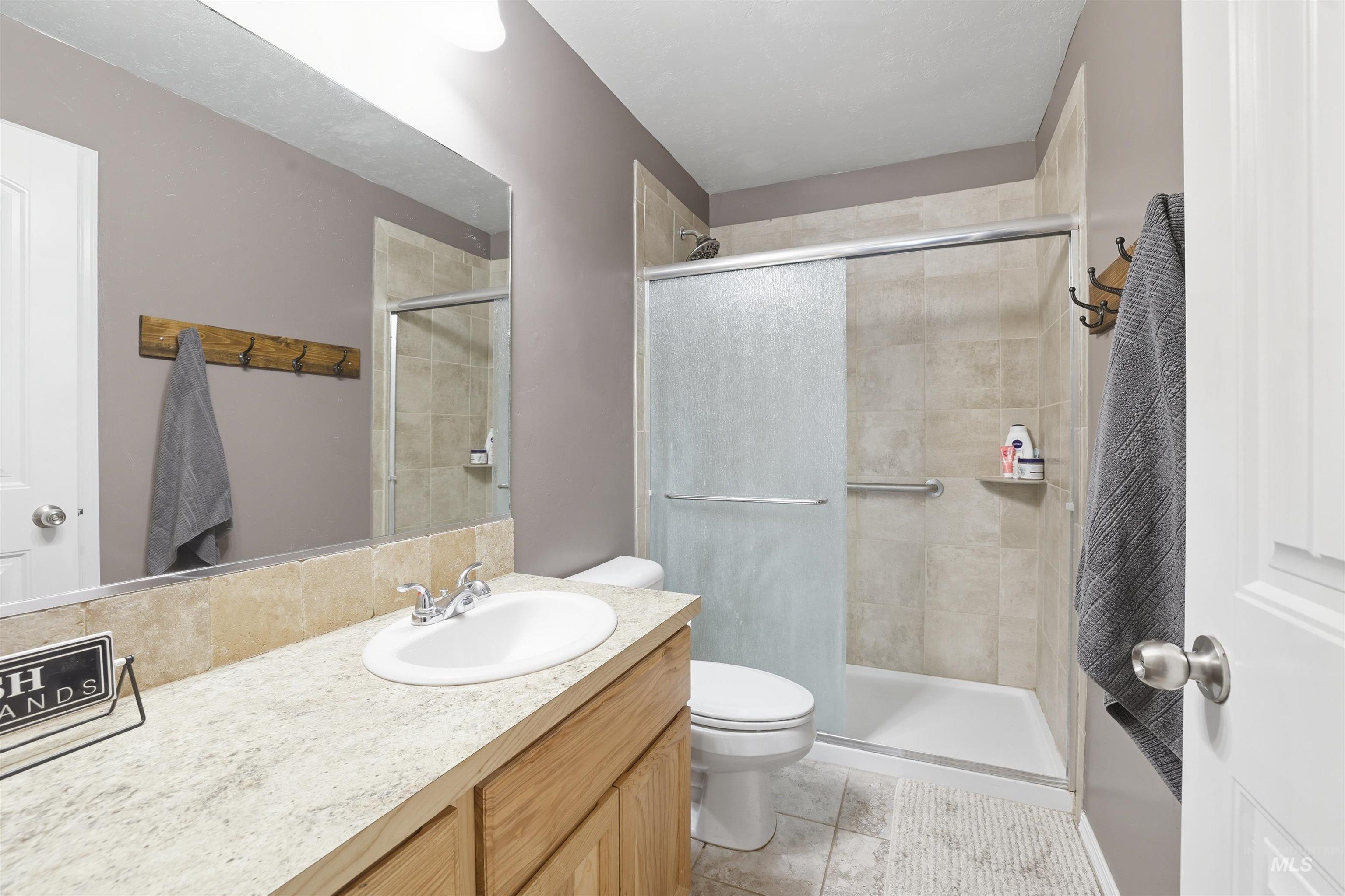 Full bath with vanity, a stall shower, and light tile patterned flooring