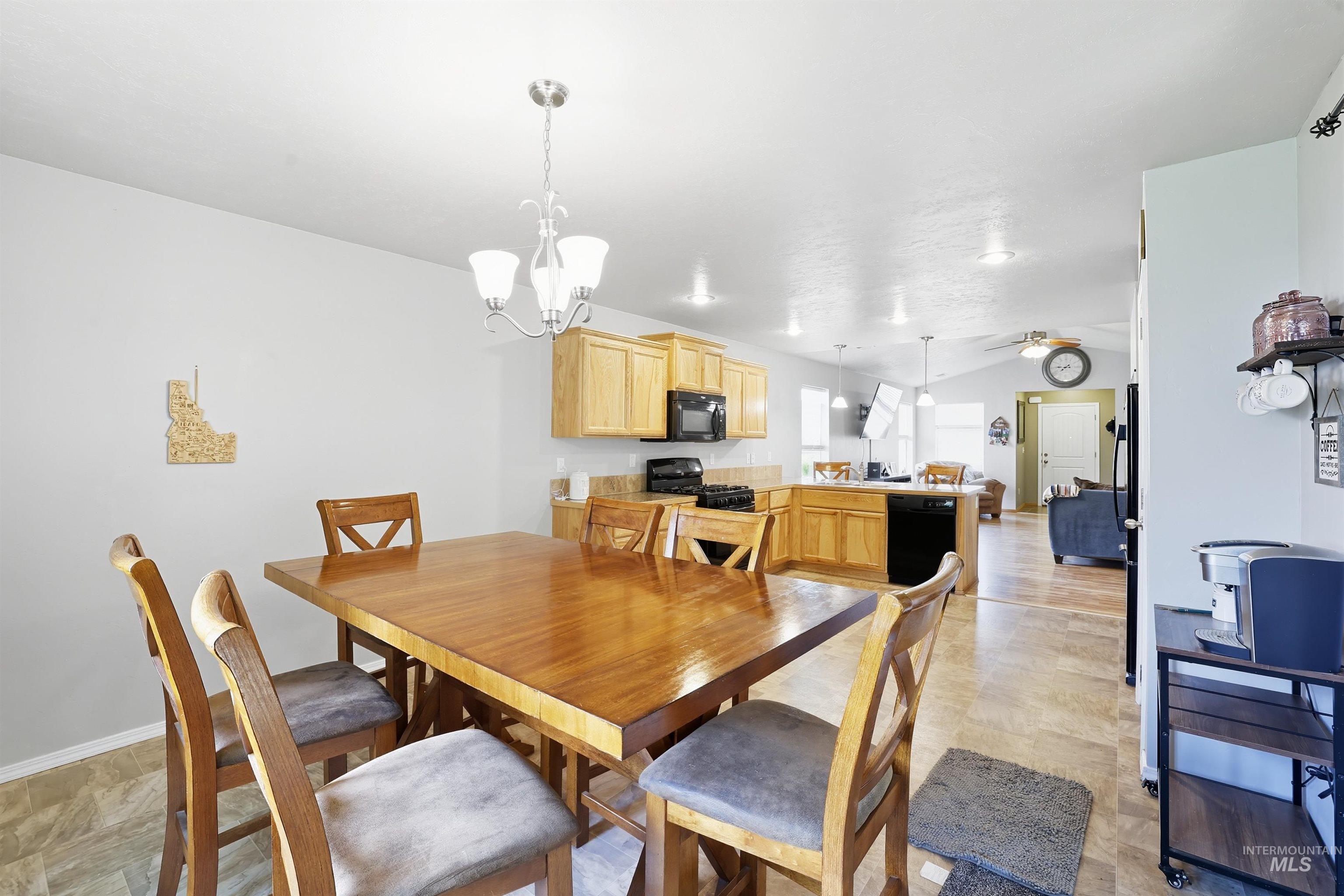 Dining space featuring a chandelier, vaulted ceiling, and ceiling fan