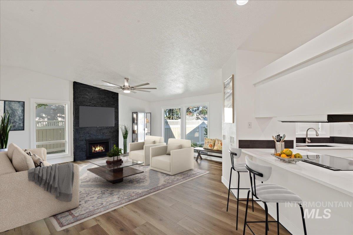 Great Room with wood finished floors, ceiling fan, plenty of natural light, lofted ceiling, and a fireplace