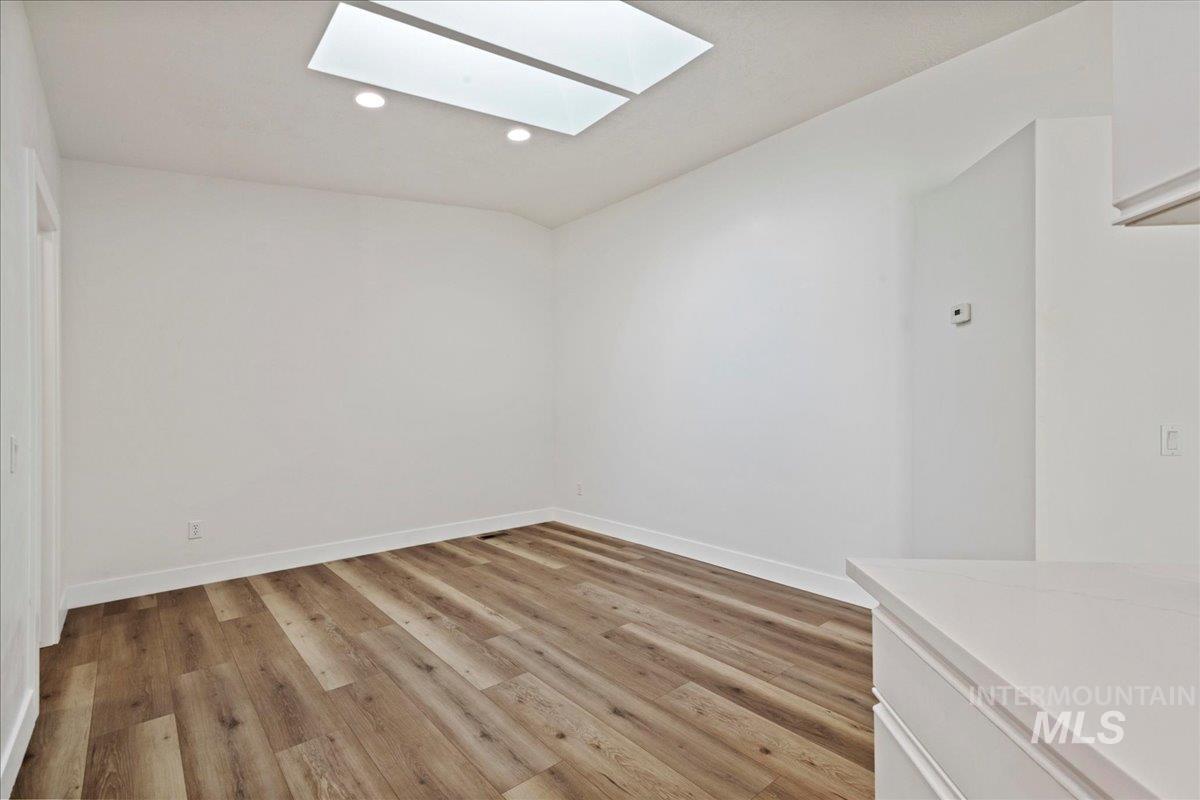 Dining Area featuring light wood-style flooring, recessed lighting, a skylight, and vaulted ceiling