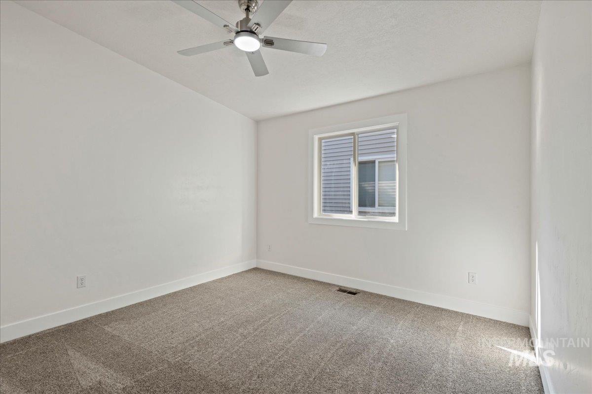 Empty room with light colored carpet and ceiling fan