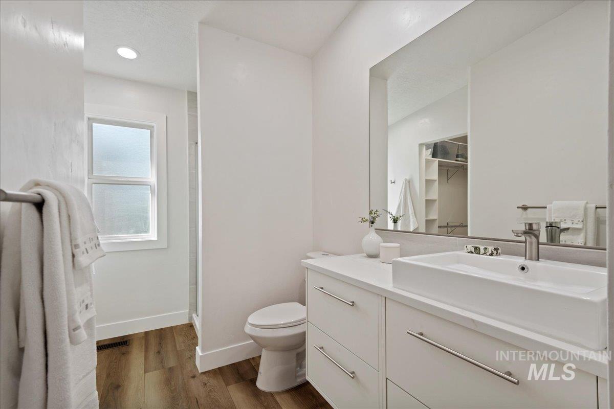 Bathroom with dark wood-style flooring, vanity, a shower stall, a walk in closet, and recessed lighting