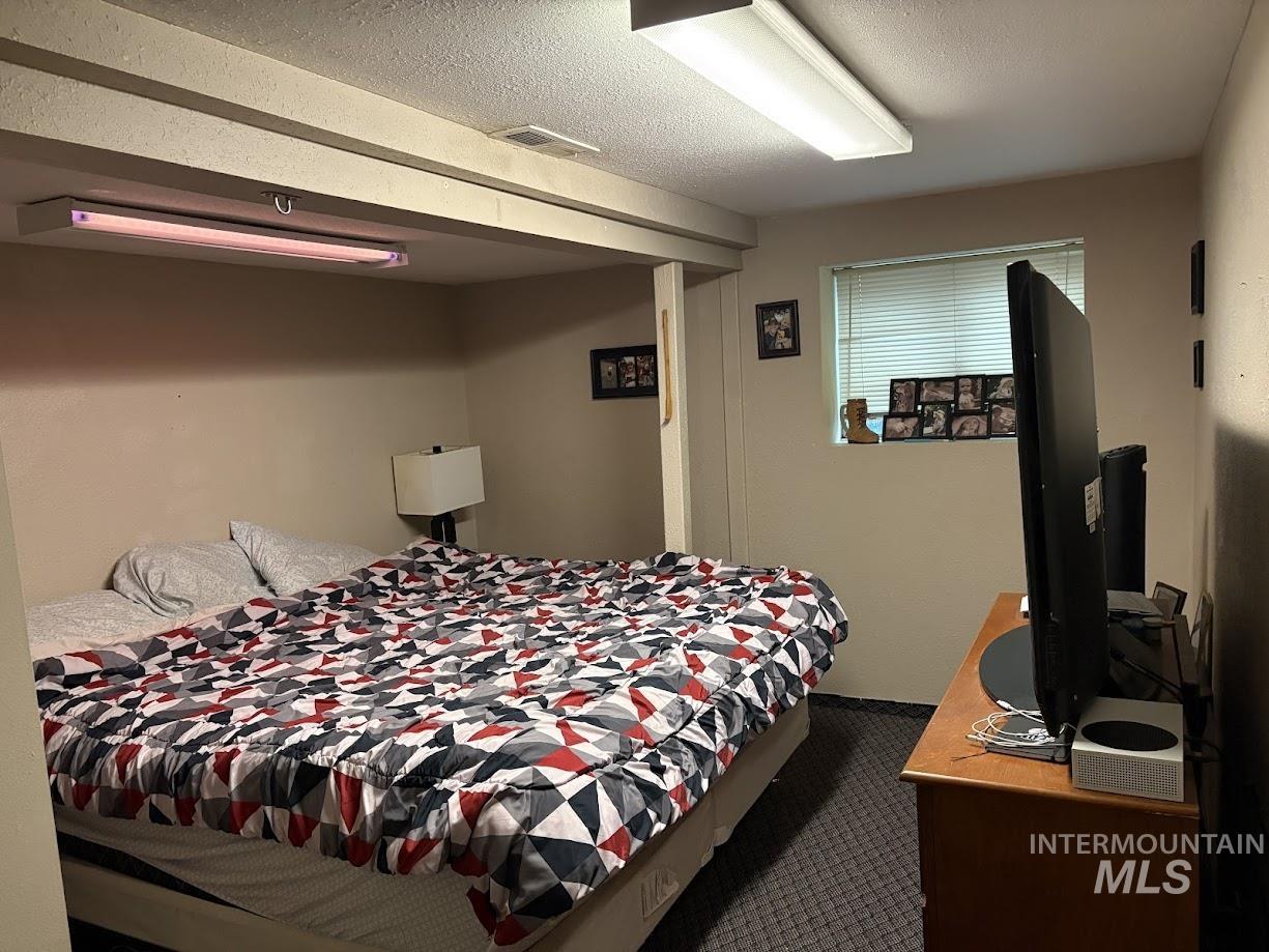 Bedroom featuring a textured ceiling and dark carpet