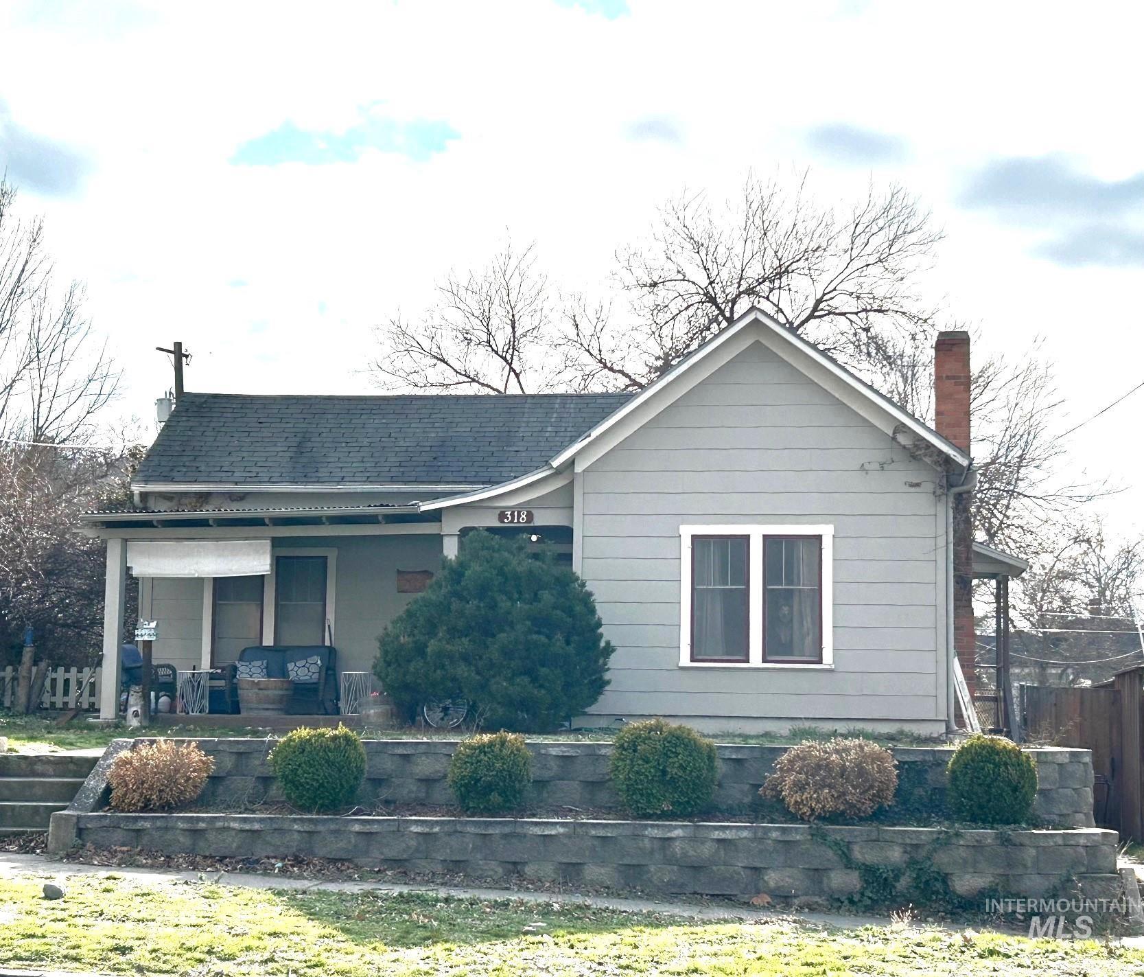 View of front of house with a porch, a chimney, and roof with shingles