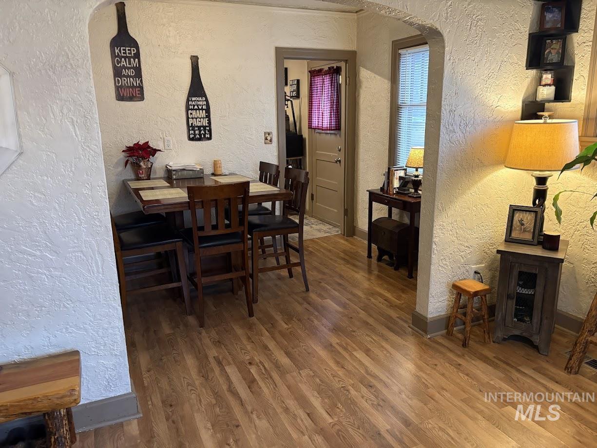 Dining area featuring a textured wall, arched walkways, and wood finished floors