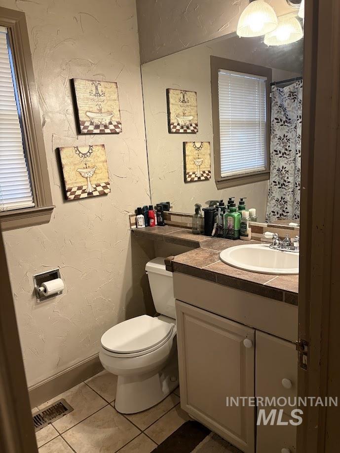 Full bathroom with a textured wall, vanity, a shower with shower curtain, and light tile patterned floors