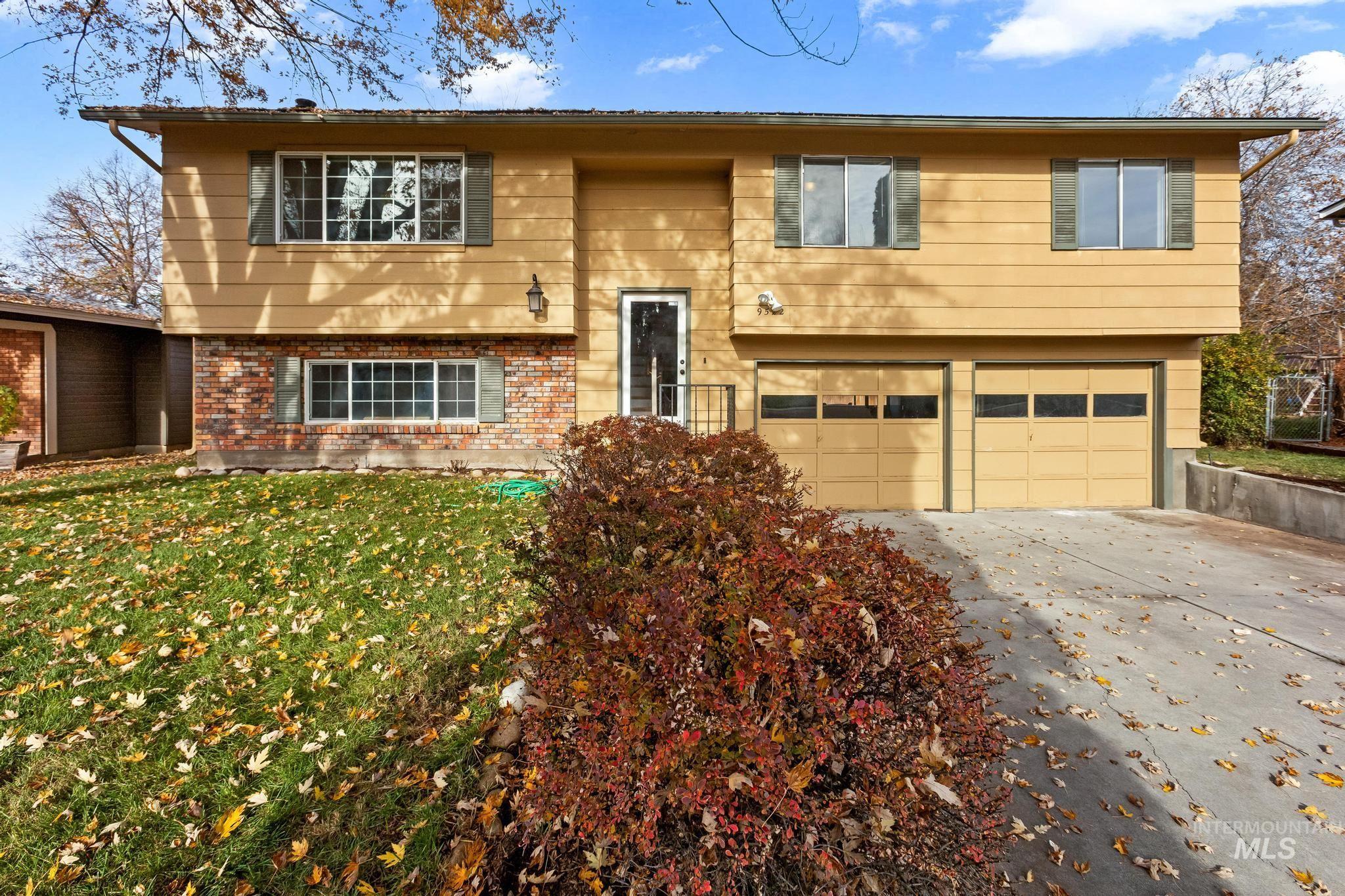 Bi-level home featuring driveway, brick siding, a garage, and a front yard