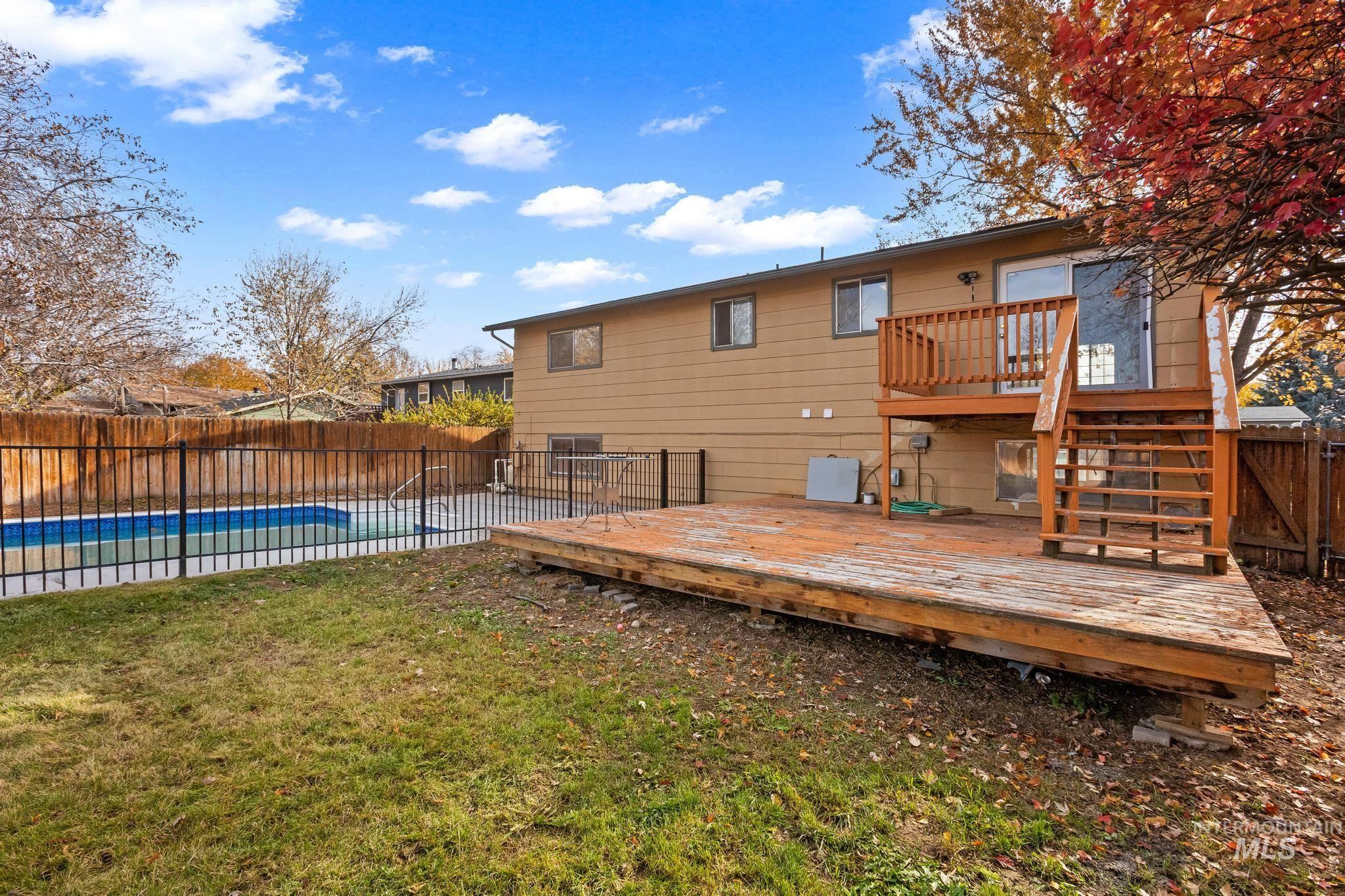 Rear view of house featuring a fenced backyard, stairway, and a wooden deck
