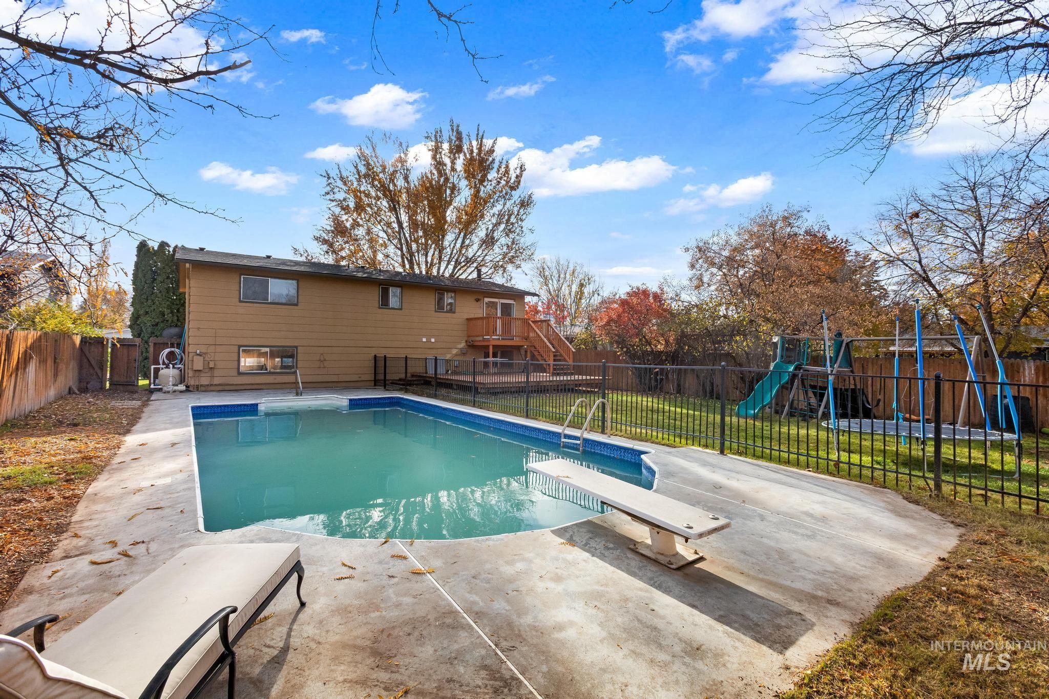 View of pool with a playground, a fenced backyard, and a diving board