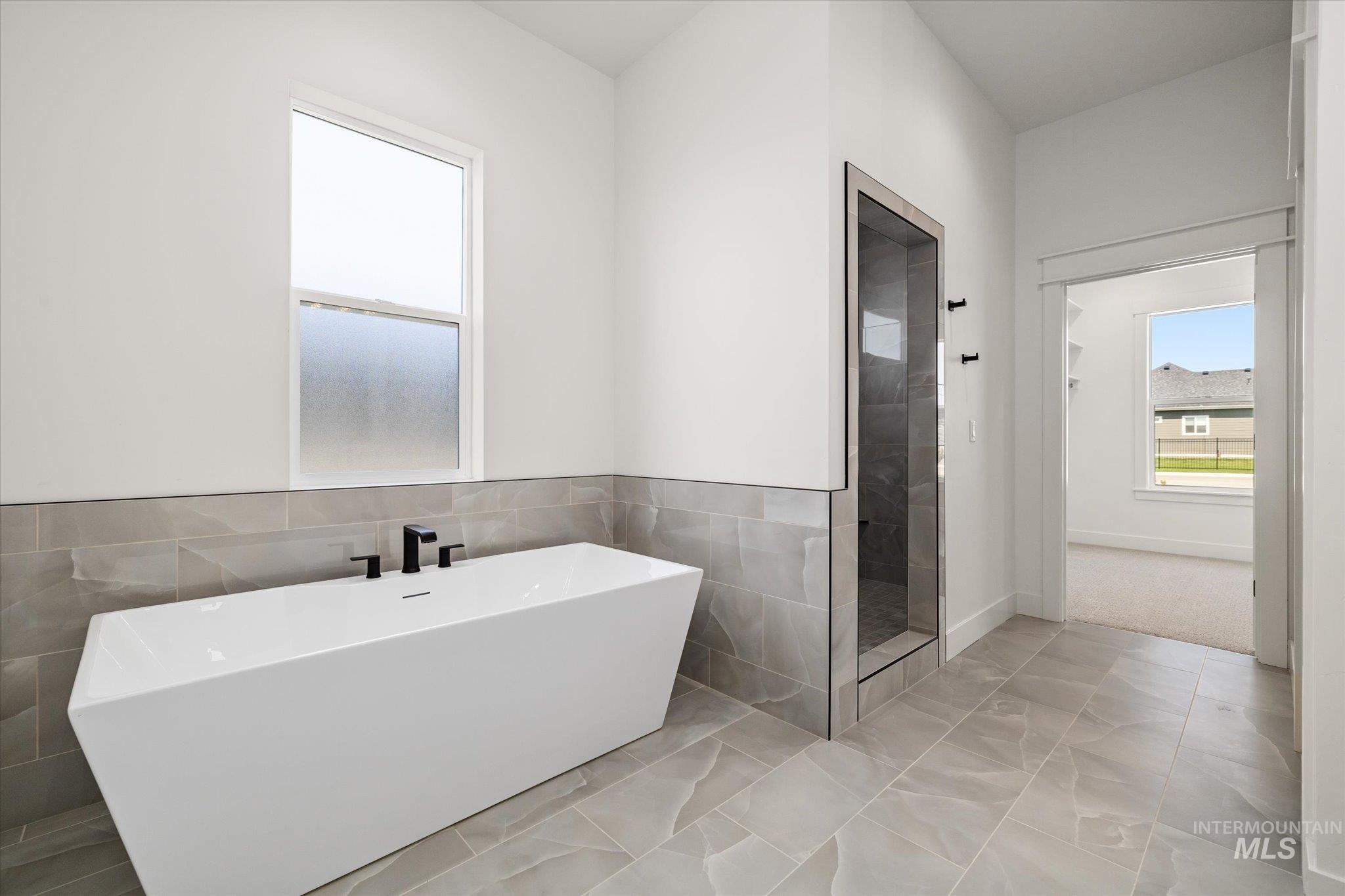 Full bath featuring a freestanding tub, a shower stall, and tile walls