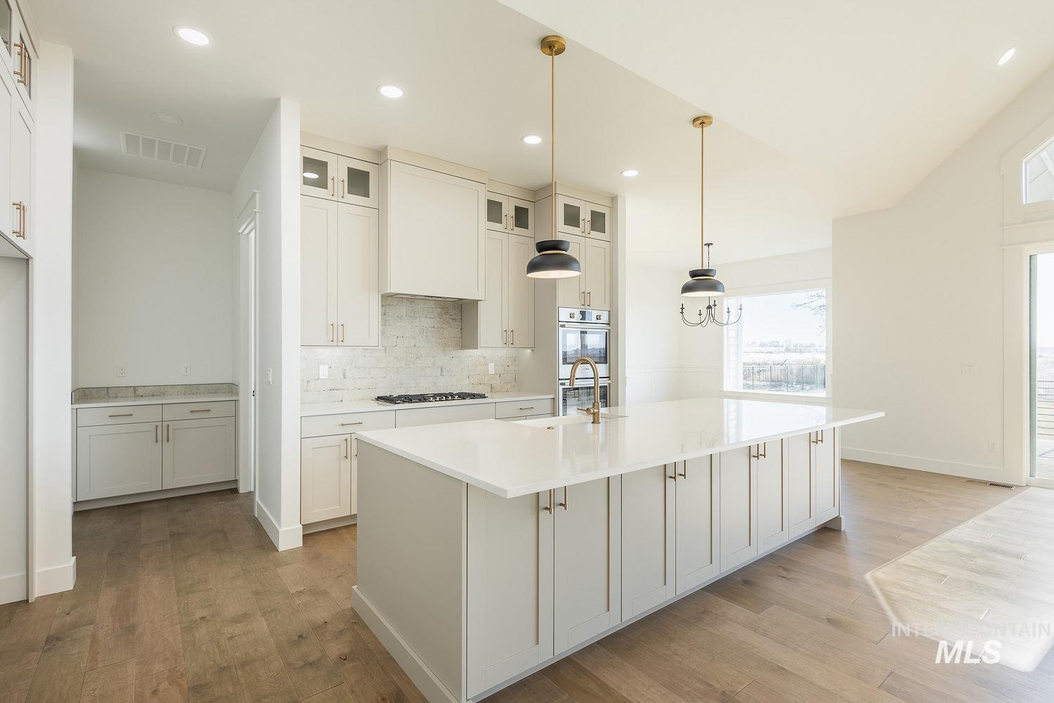 Kitchen with backsplash, healthy amount of natural light, decorative light fixtures, light wood finished floors, and recessed lighting