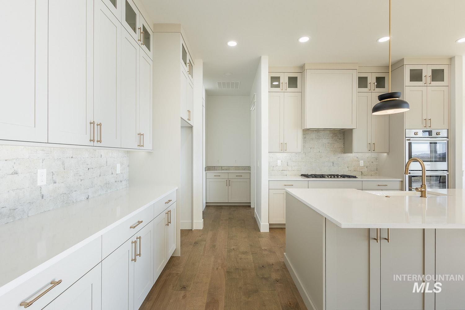 Kitchen with pendant lighting, glass insert cabinets, backsplash, recessed lighting, and dark wood-style flooring