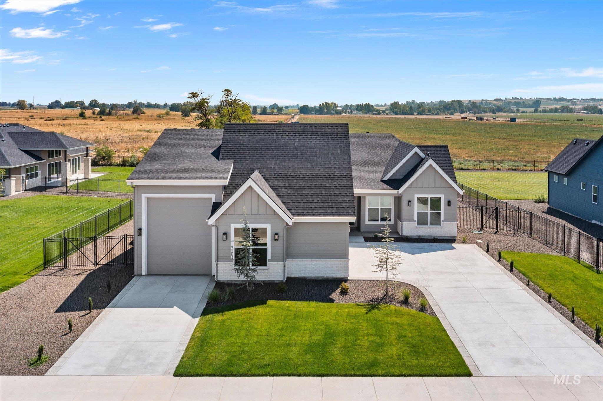 View of front of property featuring a shingled roof, a view of countryside, driveway, board and batten siding, and an attached garage