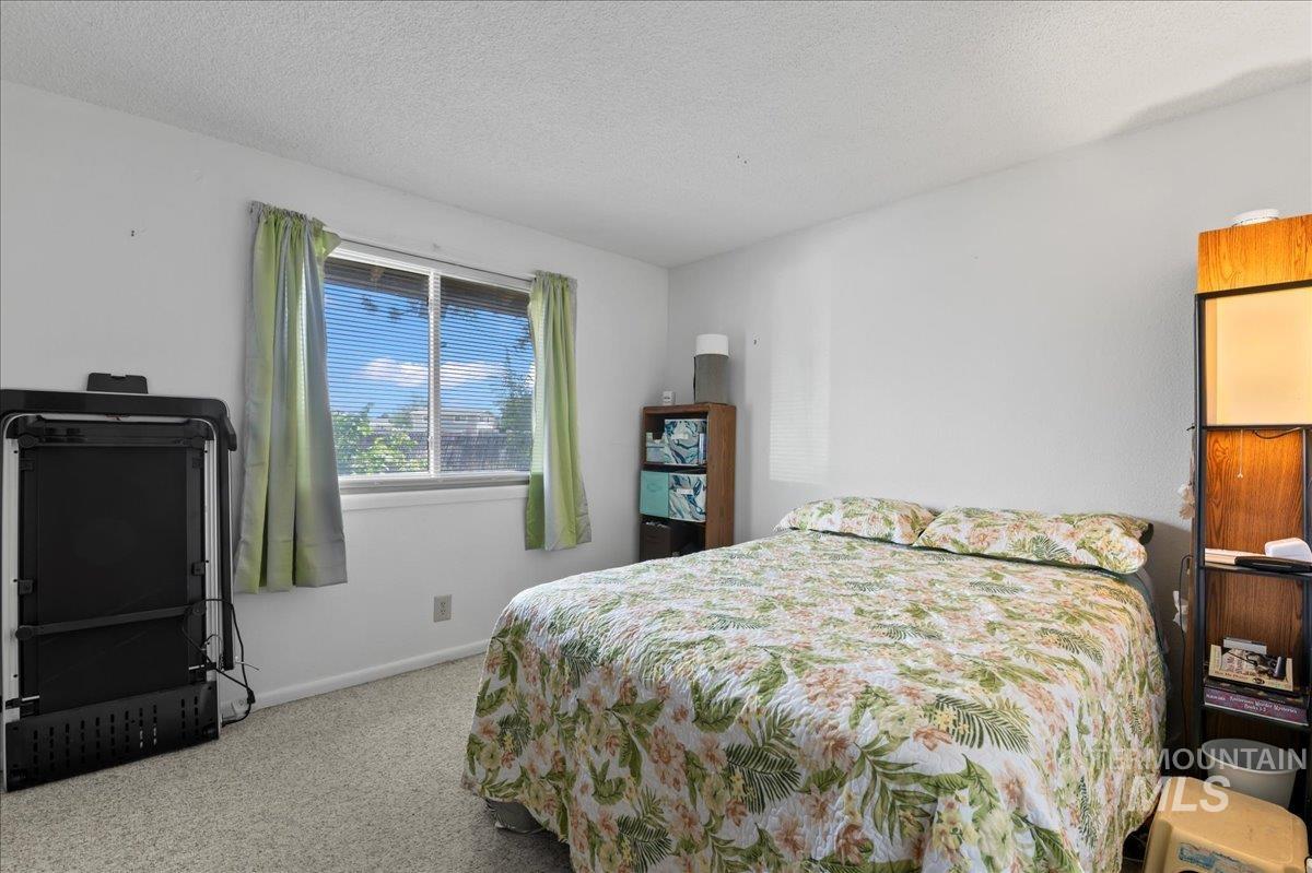 Carpeted bedroom with a textured ceiling and baseboards