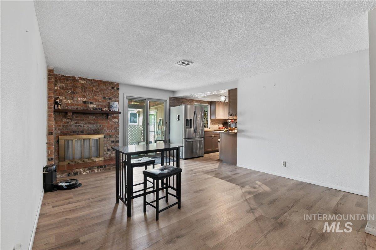 Dining space featuring light wood finished floors, a textured ceiling, and a fireplace