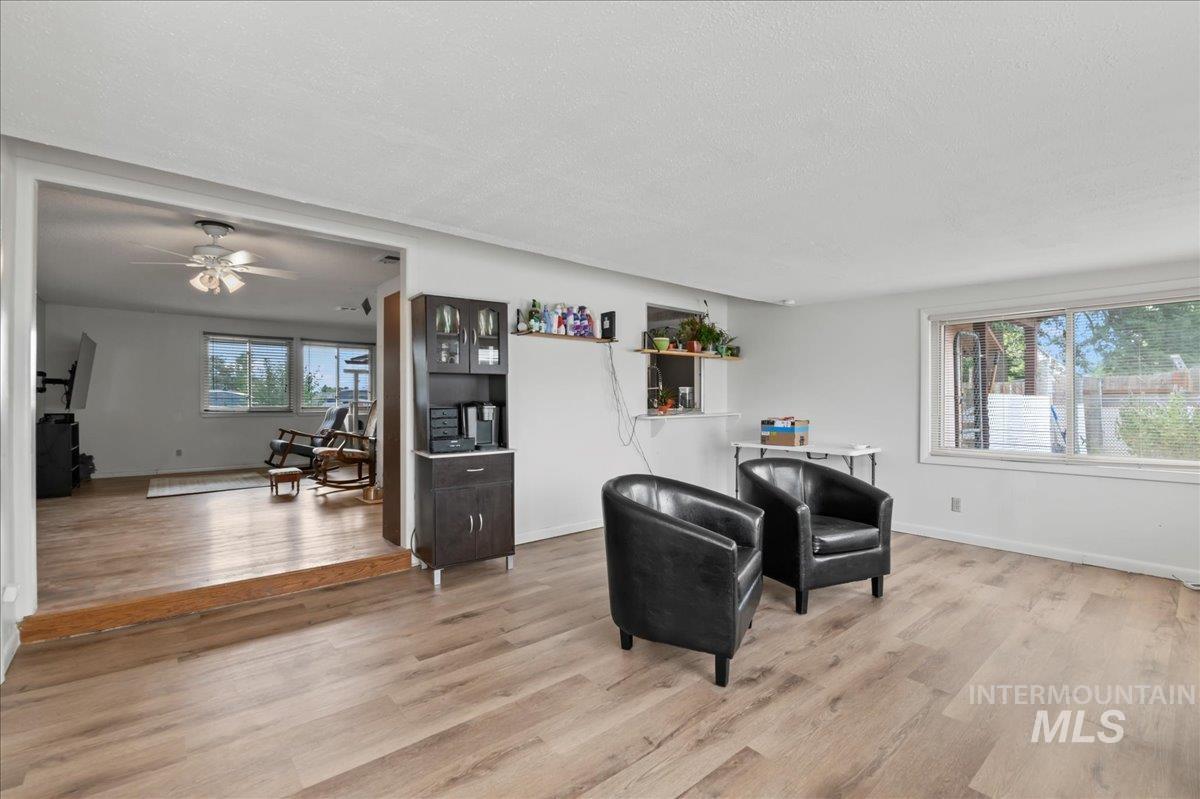 Sitting room with light wood-type flooring, ceiling fan, and a textured ceiling