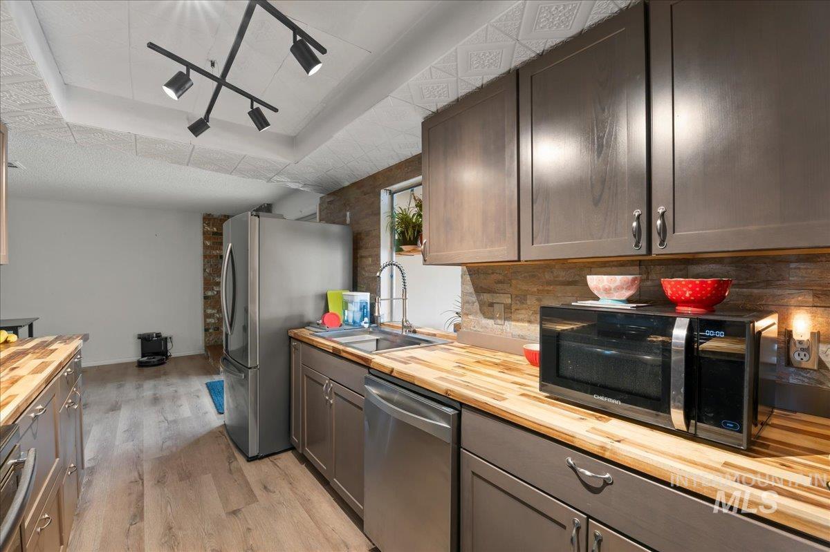 Kitchen featuring butcher block counters, a tray ceiling, appliances with stainless steel finishes, and light wood-type flooring