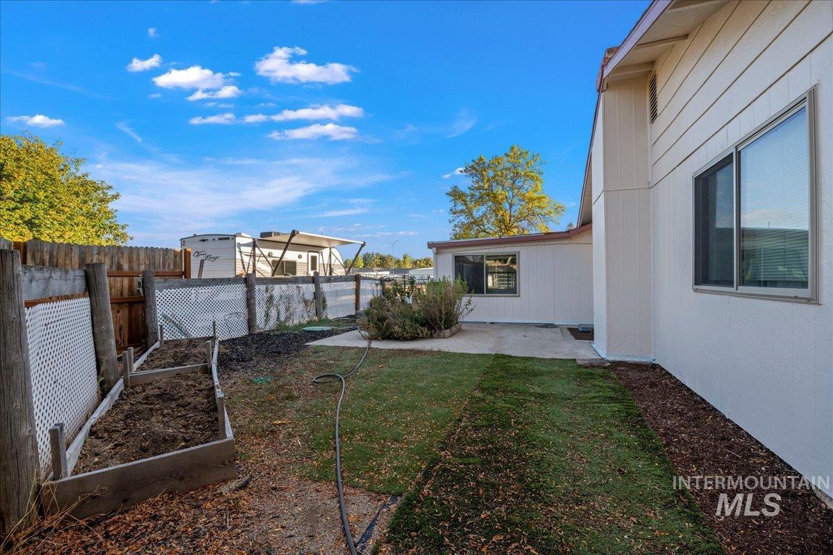 Fenced backyard with a vegetable garden and a patio