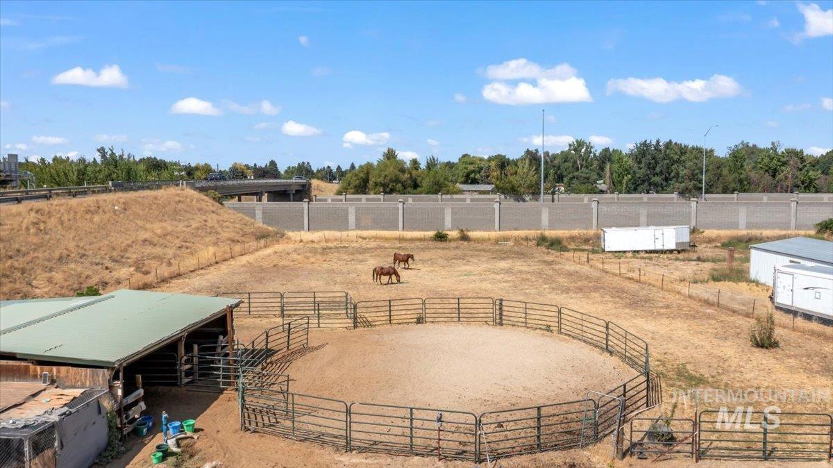 View of patio / terrace featuring a view of rural / pastoral area, an enclosed horse arena, an exterior structure, and an outbuilding