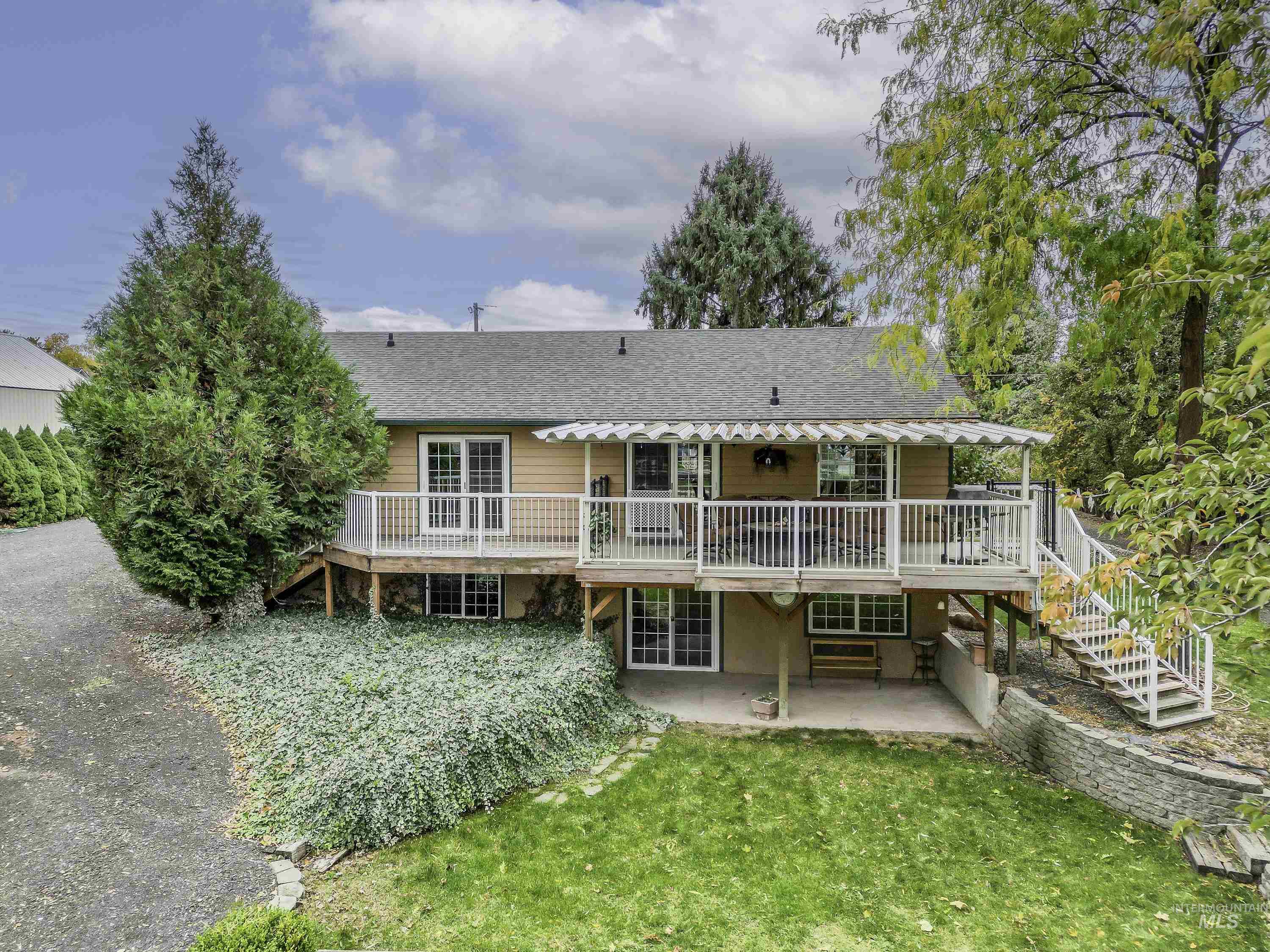 Rear view of property featuring stairway, a deck, a patio area, and roof with shingles