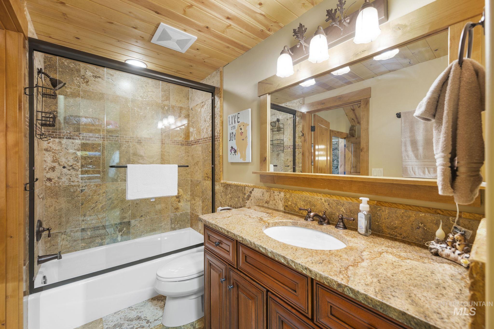 Full bathroom featuring vanity, wood ceiling, and combined bath / shower with glass door
