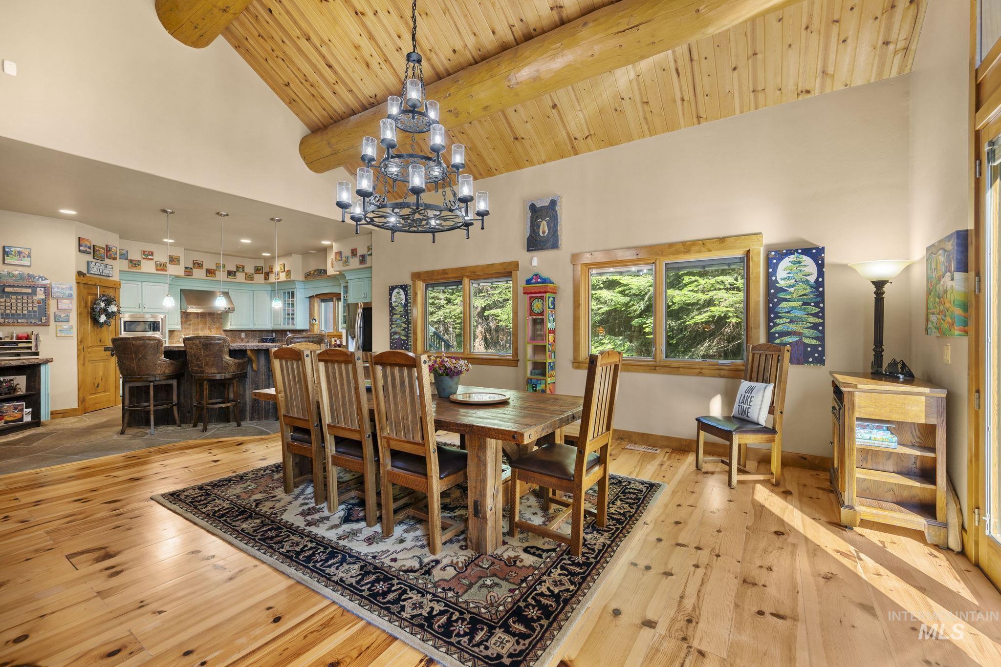 Dining room featuring light wood-style flooring, high vaulted ceiling, a chandelier, and a wood ceiling with exposed beams